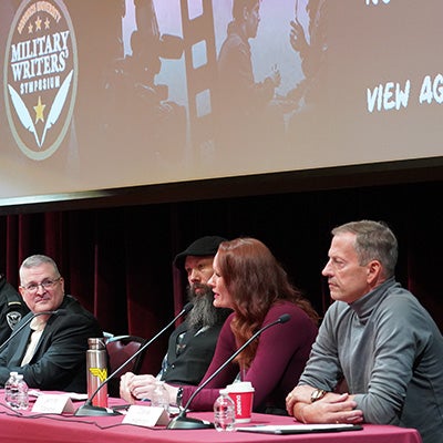 Four panelists sit behind microphones at the Norwich University Military Writers Symposium.