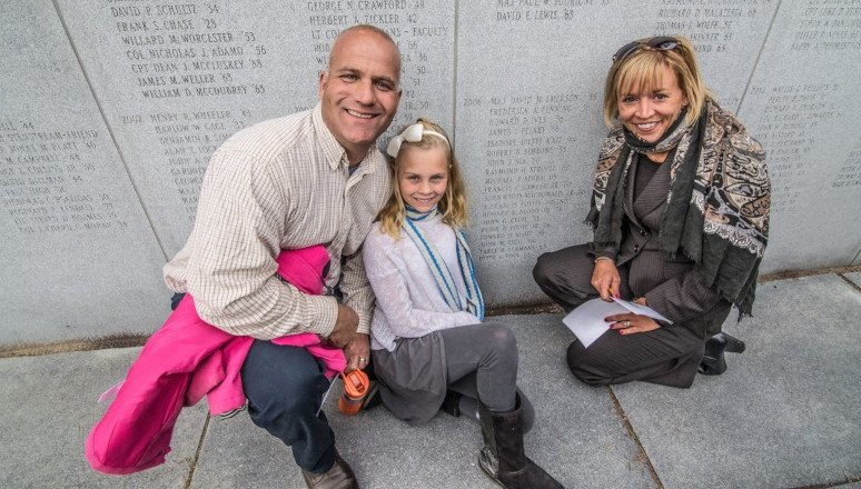 Family poses in front of the Harmon Memorial Wall