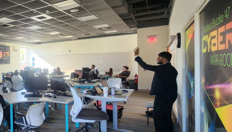 A student in a suit presents to a class of students.
