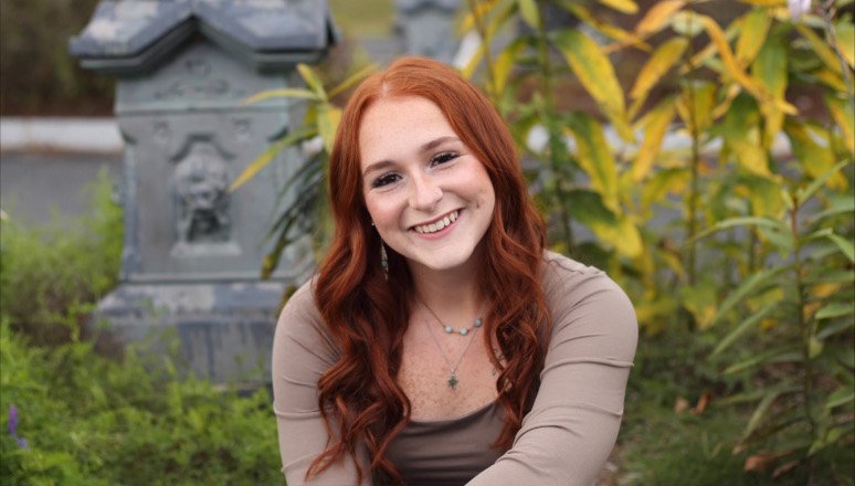 A woman smiles in a portrait taken in a garden.