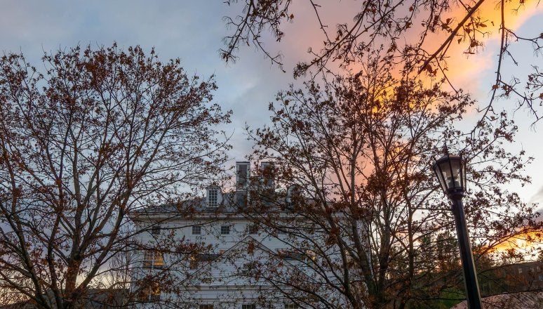 Kreitzberg Library stands behind leafless trees under a colorful evening sky